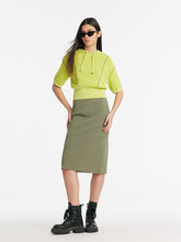 A lady wears a knitted top and a skirt.